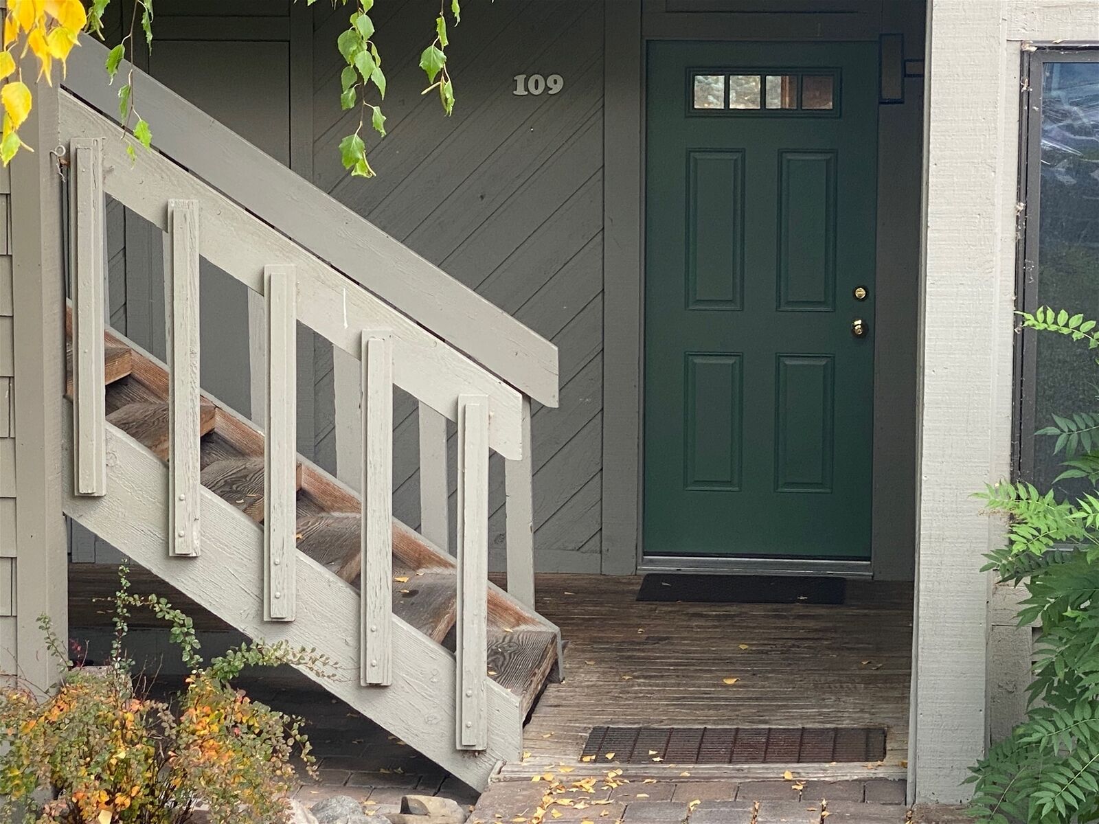 Una escalera de madera que conduce a una puerta verde con el número 109 arriba.