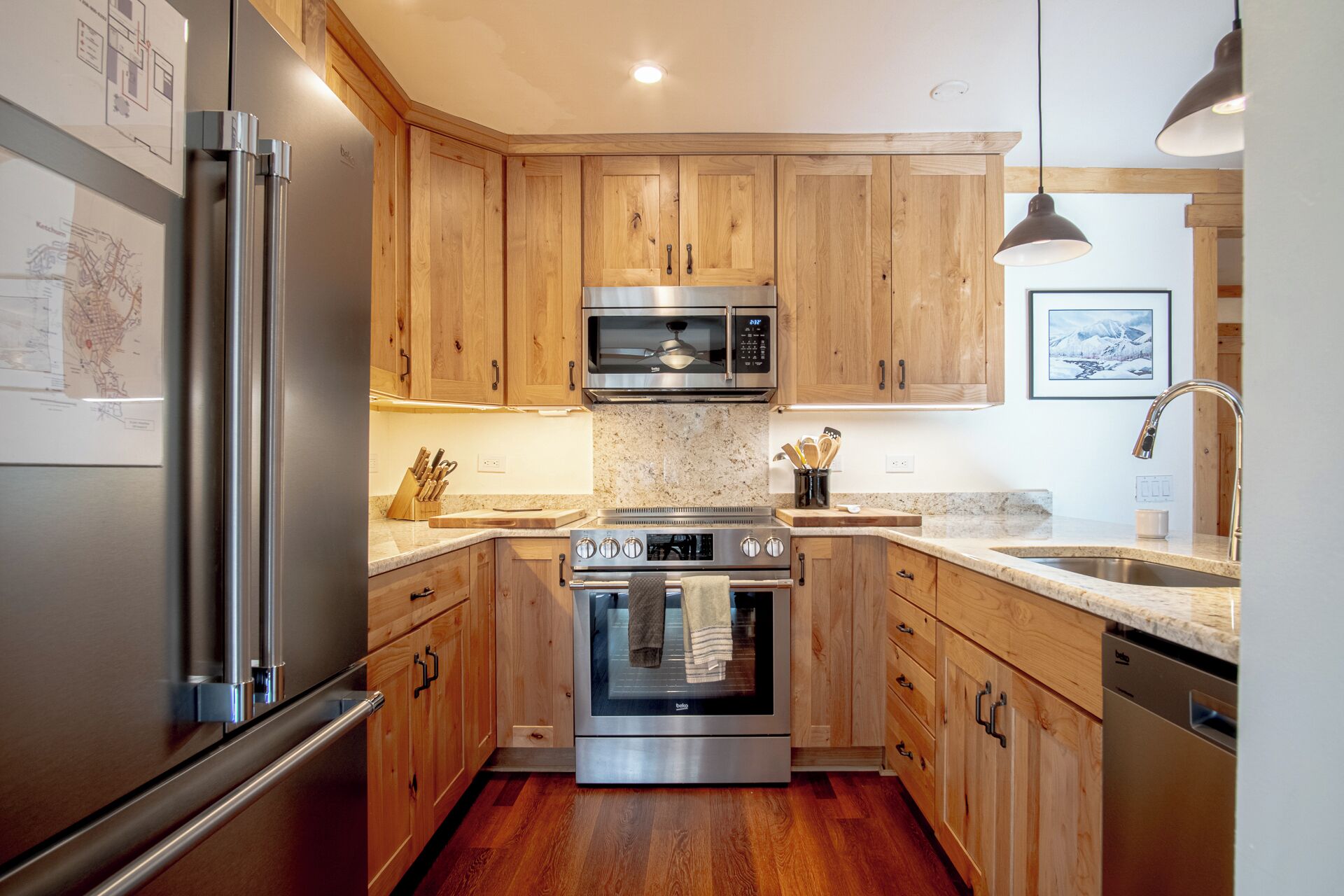 A modern kitchen with wooden cabinets, stainless steel appliances, and a granite countertop.