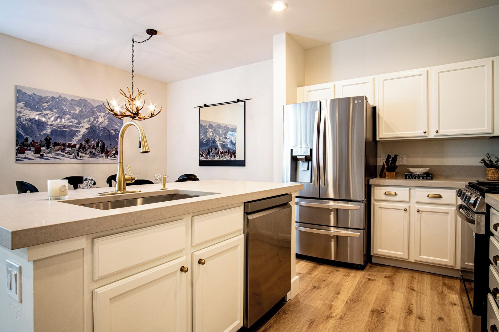 Una cocina moderna con armarios blancos, electrodomésticos de acero inoxidable y piso de madera.