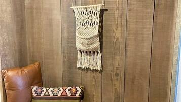 Un banco de madera con un cojín y un colgador de macramé.