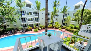 Zona junto a la piscina con mesa y sillas, rodeada por una barandilla.