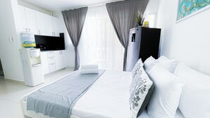Una habitación de hotel moderna con una cama, un televisor de pantalla plana, un minibar y un dispensador de agua.