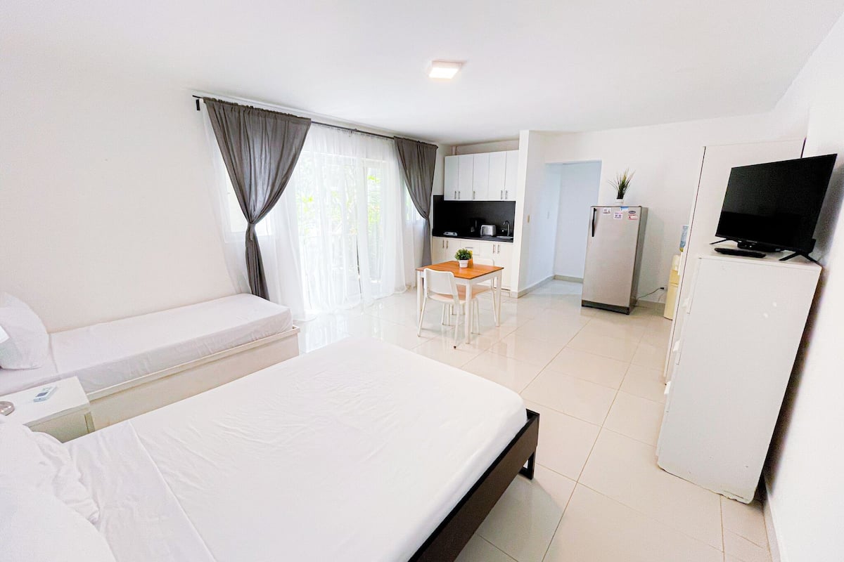 Una habitación de hotel con cama, escritorio, televisión y refrigerador.