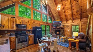 A cabin with a kitchen, dining area, and fireplace. - Secluded Cabin for 4 w/ Private Hot Tub & Jacuzzi! (Sevierville)