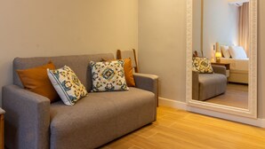 En moderne stue med en grå sofa, mønstrede puder og et stort spejl, der reflekterer rummet.