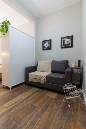 Ein modernes Wohnzimmer mit einem grauen Sofa, einer weißen Kommode und zwei gerahmten Blumenbildern an der Wand.
