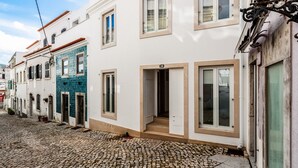 Una estrecha calle adoquinada flanqueada por edificios tradicionales, con fachadas en blanco y azul y un llamativo letrero con el número 38.