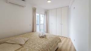 Un dormitorio con cama, armario, aire acondicionado y ventana con cortinas.