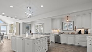 A spacious kitchen with white cabinetry, a large island, and a dishwasher. - Steps to beach with views galore! (Emerald Isle)