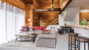 Et hyggeligt interiør i en træhytte med en ternet sofa, et træbord og en bar.
