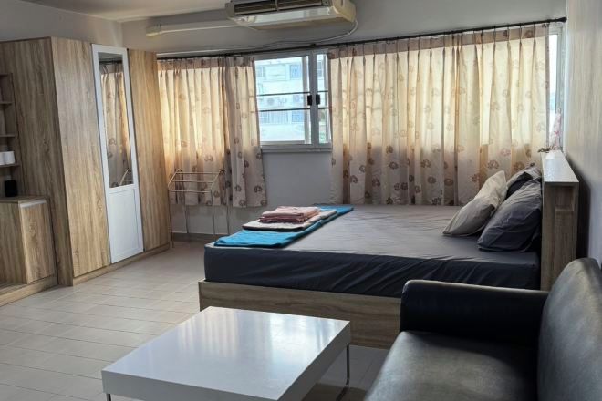A room with a bed, a sofa, a table, and a window with curtains.