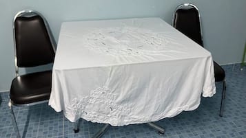 A square table with a white tablecloth, two black chairs, and a patterned floor.