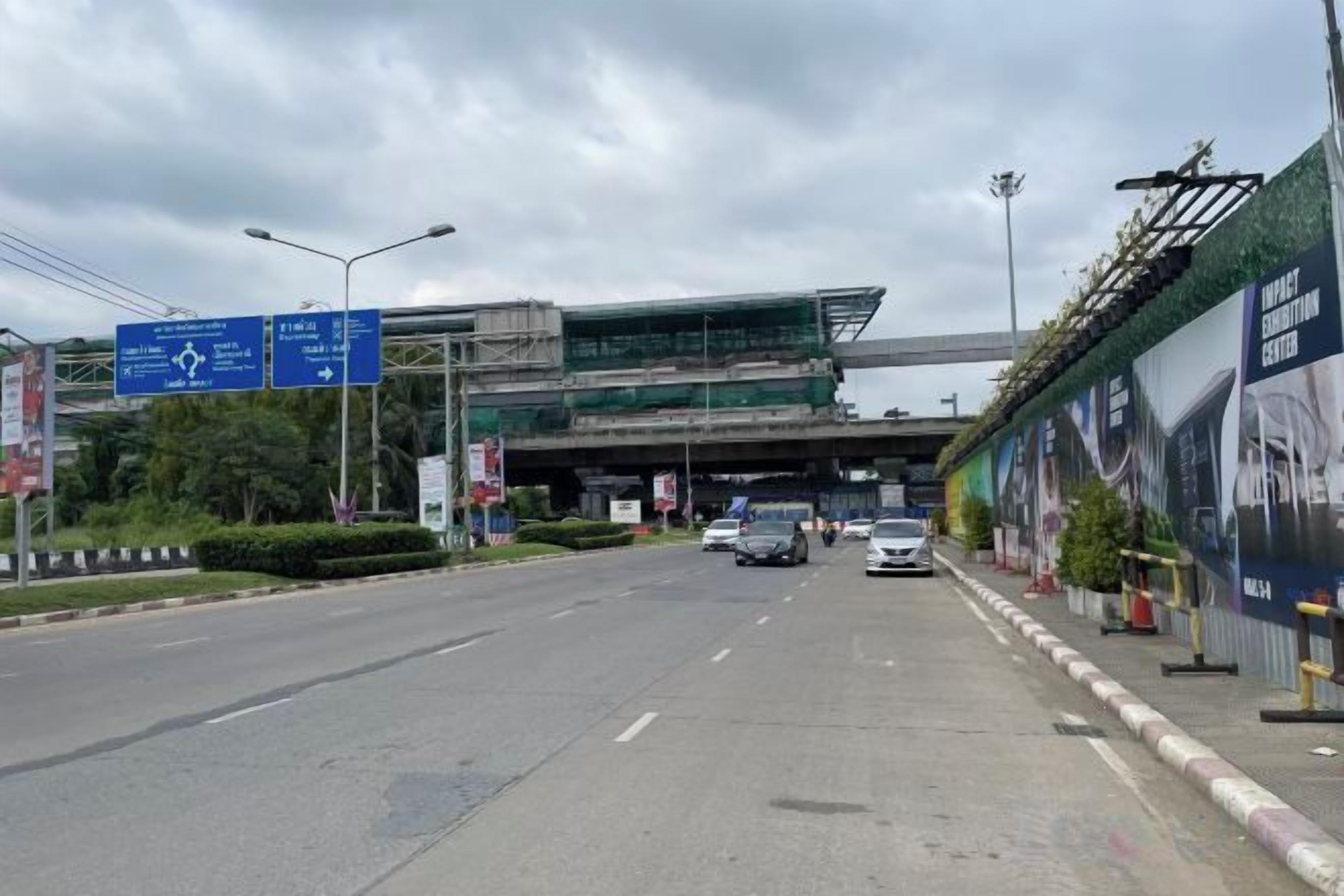 Eine mehrspurige Straße mit Hinweisschildern über dem Verkehr, ein Fußweg und ein Gebäude im Bau.