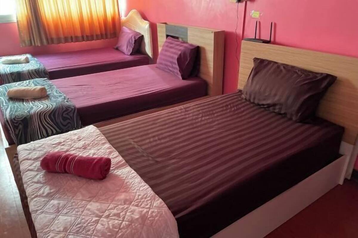 Habitación de hotel con tres camas, cada una con un diseño de cabecera diferente.