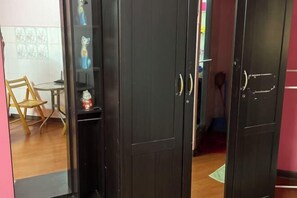 A room with a wooden floor, a black wardrobe, and a small table with a chair. - Impact Dailyroom C1,C9 by Anna (Pak Kret)