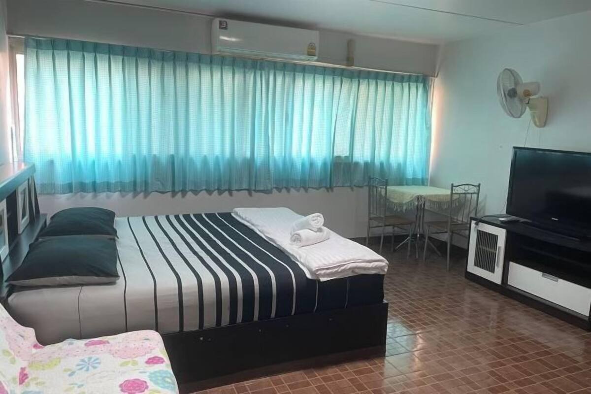 Una habitación de hotel con cama, televisor, escritorio y silla.