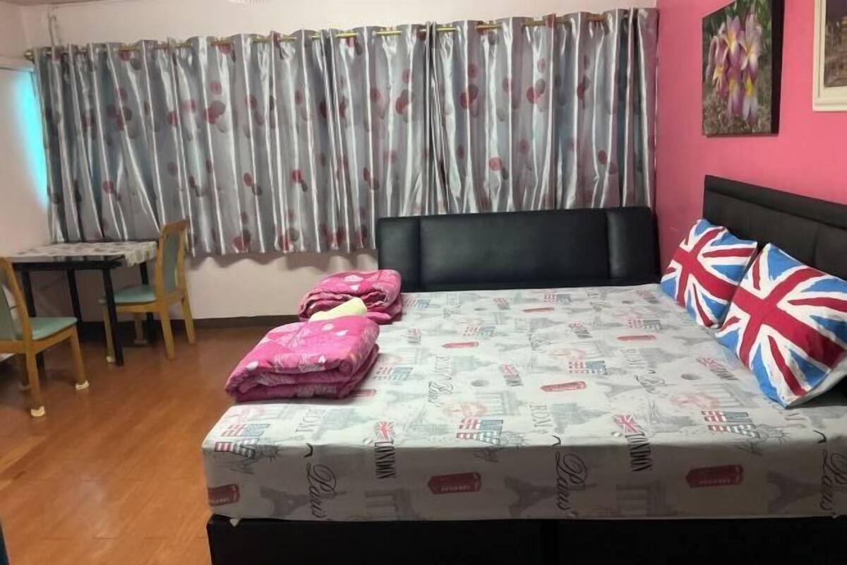 Un dormitorio con cama, mesa, sillas y una cortina.