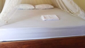 Un lit doté d’un baldaquin blanc, de deux oreillers et d’une serviette blanche pliée.