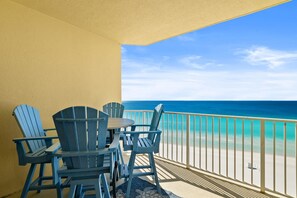 Ein Balkon mit Blick auf das Meer, ausgestattet mit einem Tisch und vier Adirondack-Stühlen.