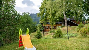 A playground with a slide and swings, surrounded by trees and a house in the background. - Apartment 'Reesbauernhof - Fewo Abendrot' with Mountain View, Shared Terrace & Wi-Fi (Oberried)