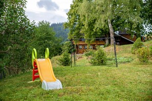 A playground with a slide and swings, surrounded by trees and a house in the background. - Apartment 'Reesbauernhof - Fewo Abendrot' with Mountain View, Shared Terrace & Wi-Fi (Oberried)
