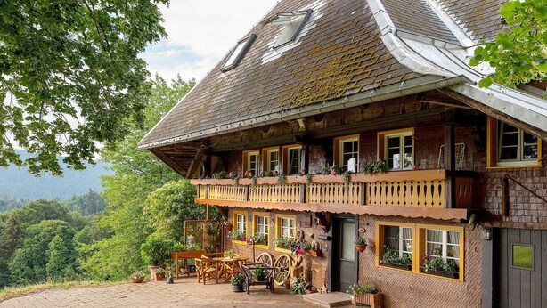Ein traditionelles Chalet mit Balkon, Holzmöbeln und Topfpflanzen.