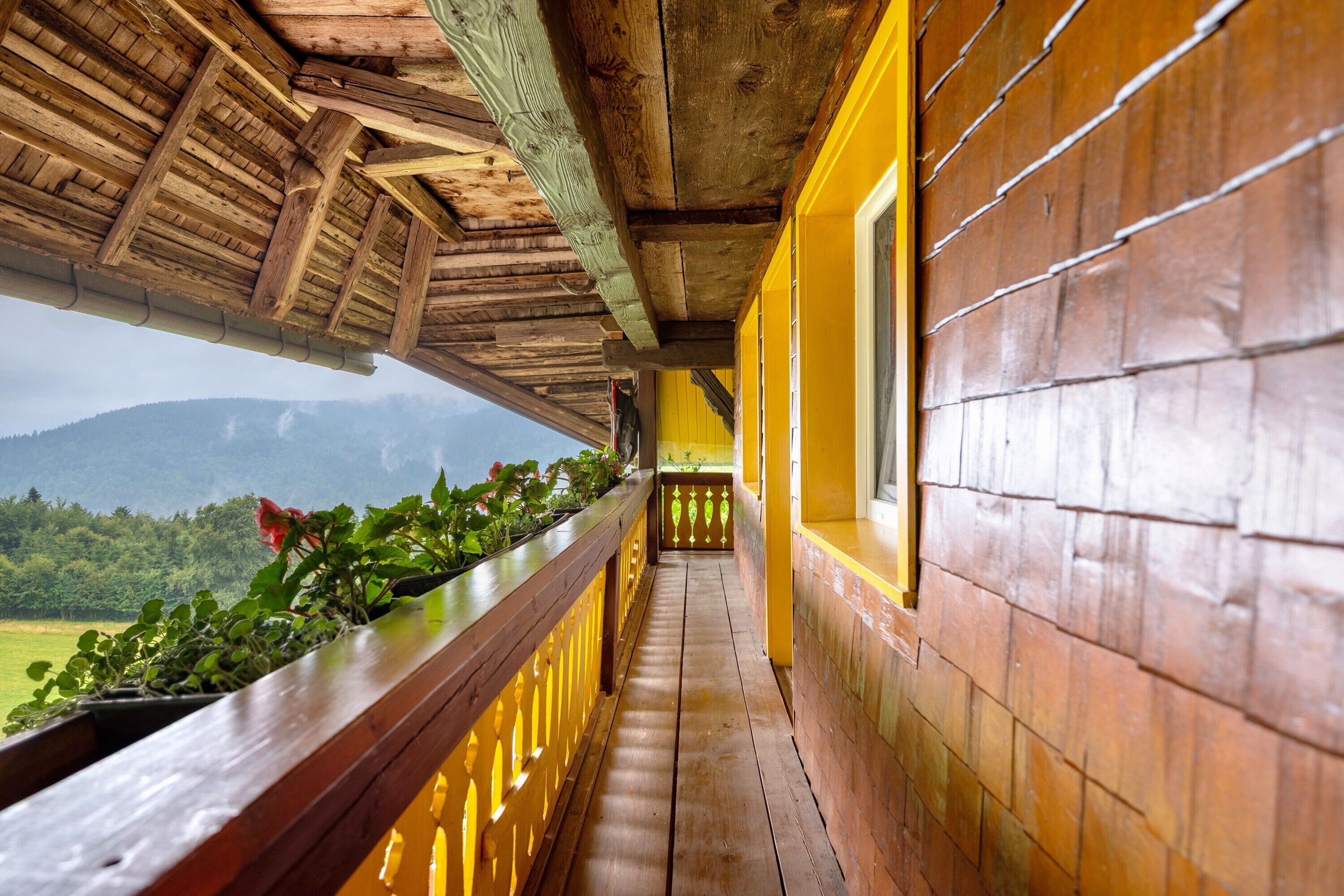 Ein hölzerner Balkon mit Blick auf eine grüne Landschaft und Berge.