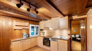Eine Küche mit Holzschränken, einem eingebauten Backofen, einer Kaffeemaschine und einem Fenster.