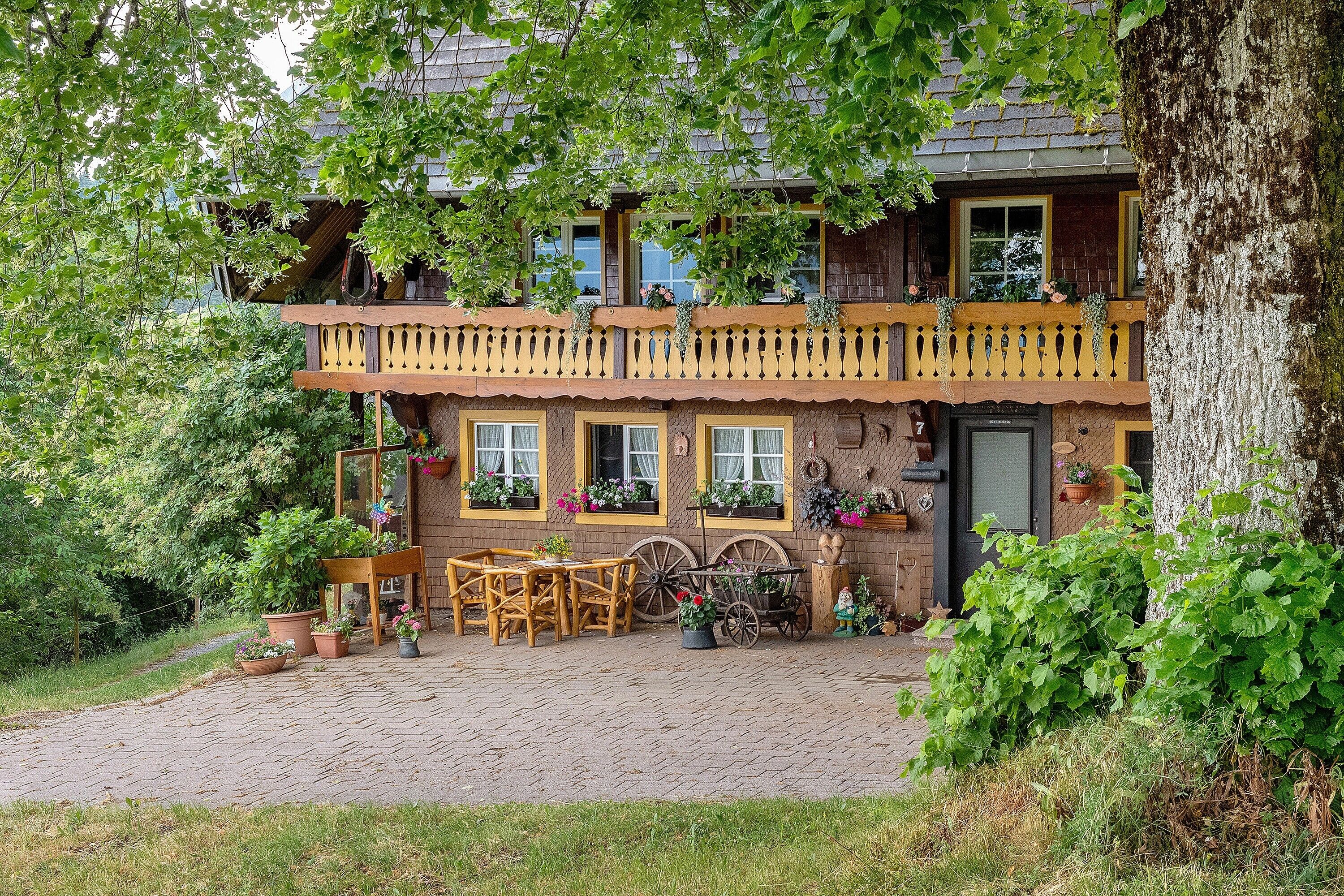 Ein traditionelles Holzhaus mit Balkon, Kamin und Kopfsteinpflasterauffahrt.