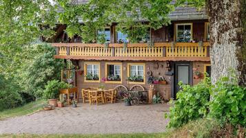 Ein traditionelles Holzhaus mit Balkon, Kamin und Kopfsteinpflasterauffahrt.