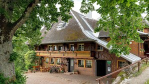 Ein traditionelles Chalet mit Holzbalkon, einer Steinfassade und einem gepflasterten Innenhof.