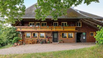 Ein traditionelles Holzhaus mit Balkon, Blumentöpfen und einem Backsteinweg.