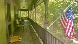 Un portico riparato con vista su una foresta, una bandiera americana e una panchina.