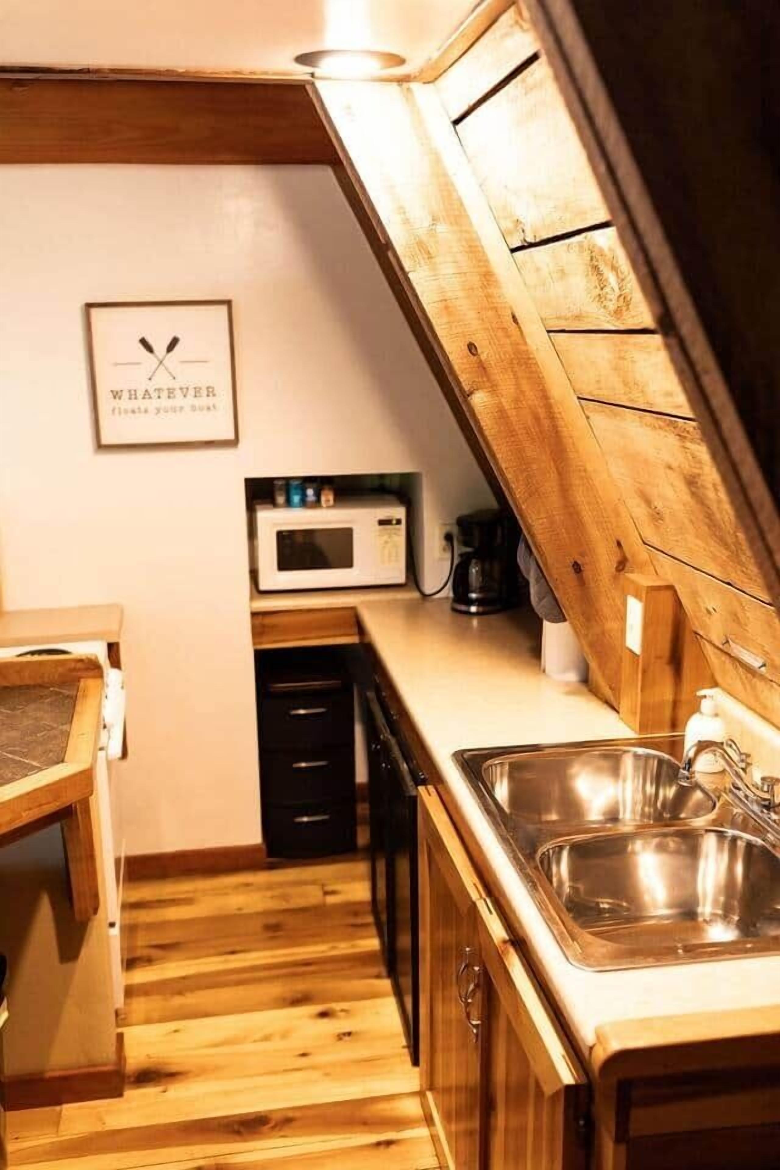 Une cuisine de taille réduite, dotée de meubles en bois, d’un four à micro-ondes et d’un évier.