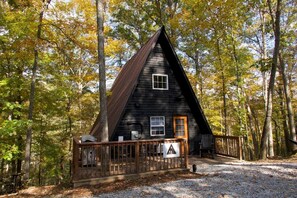 A cabin with a triangular roof, surrounded by trees. - Grin and Bear It | Indoor Jacuzzi Tub (Powell County)