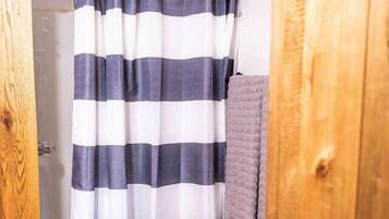 A bathroom with a striped shower curtain, a wooden door, and a towel rack.