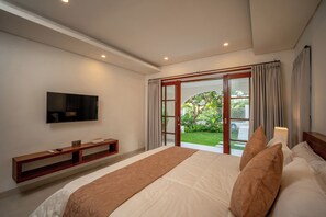 A modern bedroom with a large bed, a TV mounted on the wall, and a sliding glass door leading to a garden. - 3 bed room Villa Rice View Terrace in Bali (Sukawati)