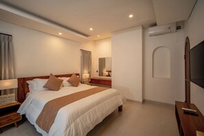 Ein Hotelzimmer mit einem großen Bett, Nachttischen, einem Fernseher und einem Spiegel.
