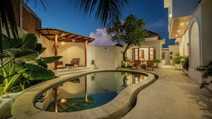 A swimming pool with a curved design, surrounded by a patio area with seating and plants. - 3 bed room Villa Rice View Terrace in Bali (Sukawati)
