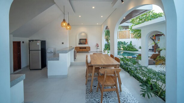 A modern kitchen with a central island, built-in appliances, and a dining area with a wooden table and chairs. - 3 bed room Villa Rice View Terrace in Bali (Sukawati)