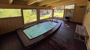 Ein Hallenbad mit Holzterrasse, großen Fenstern und Sicherheitshinweisen.