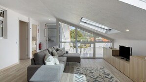 Un salon moderne avec un canapé, un téléviseur et une grande fenêtre.
