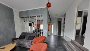 Een moderne woonkamer met een grijze bank, een rode fauteuil en een houten salontafel.