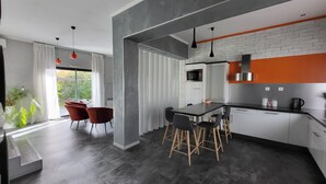 Een moderne keuken met een eethoek, voorzien van een groot raam, een magnetron en een koffieapparaat.