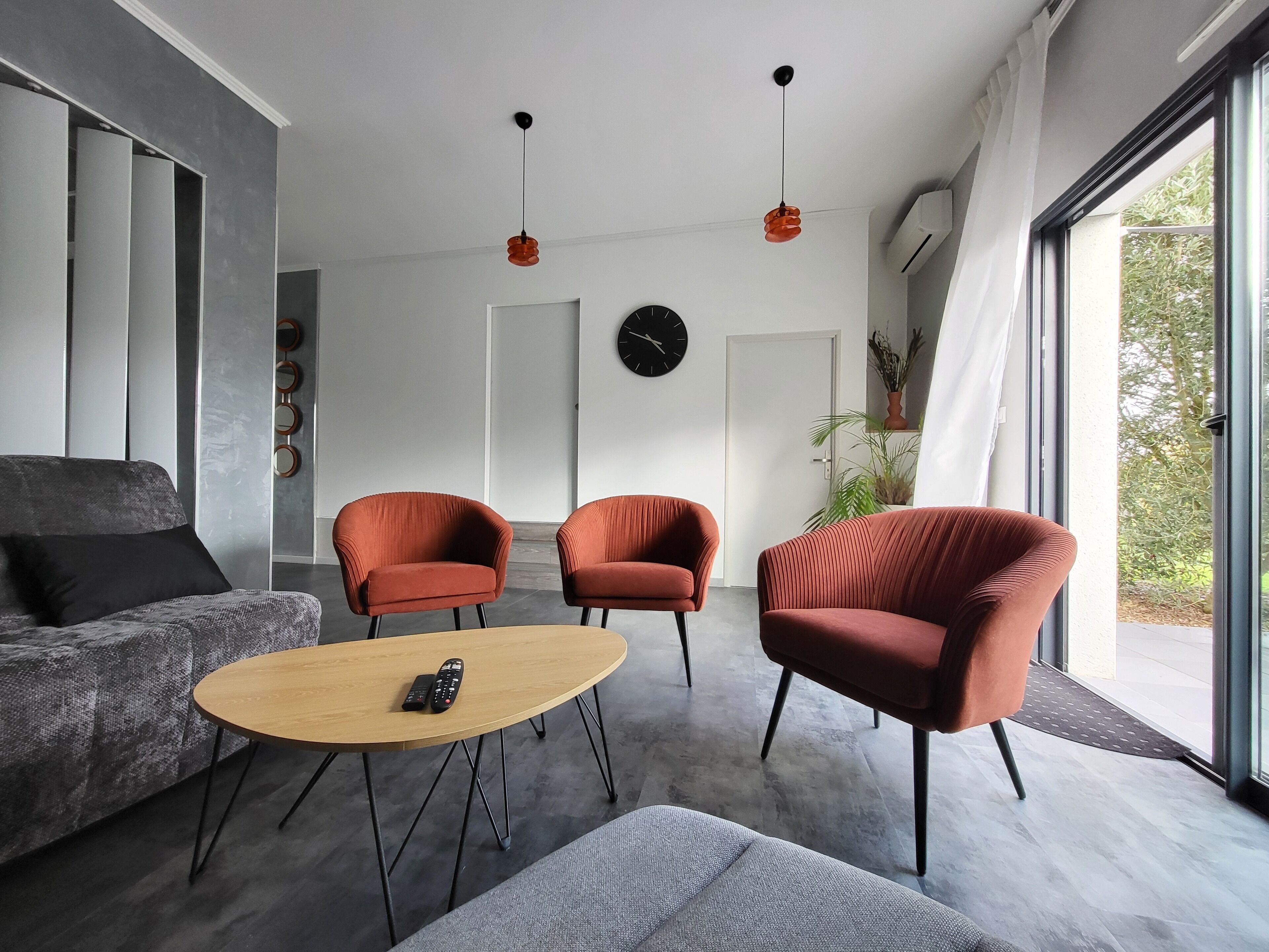 A modern living room with a sofa, two armchairs, a coffee table, and a large window.