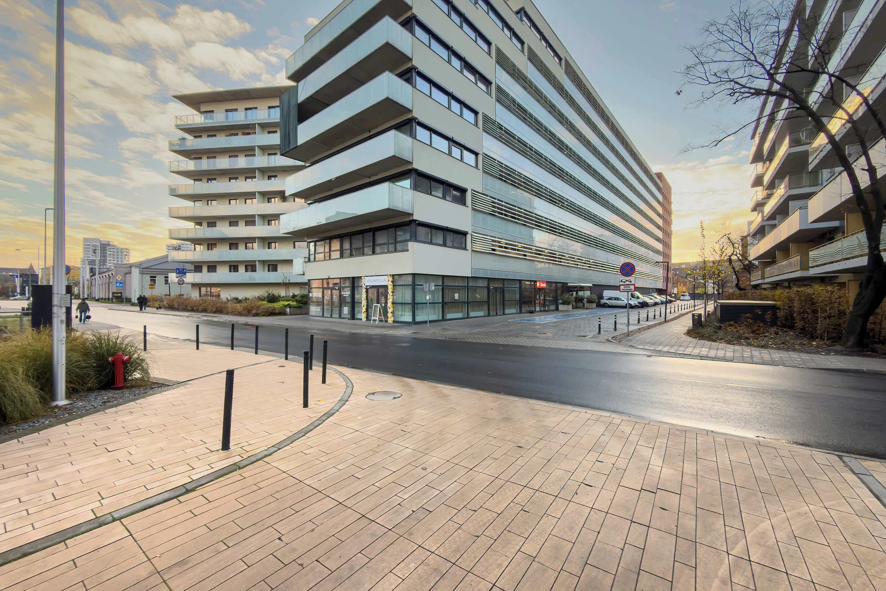 A modern multi-story building with a flat facade, large windows, and a pedestrian walkway.