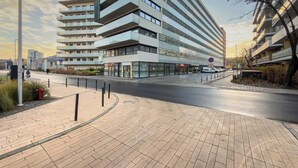 A modern multi-story building with a flat facade, large windows, and a pedestrian walkway. - Modern Apartment | Air Conditioning | Spa and Gym | Parking. (Wrocław)