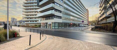 A modern multi-story building with a flat facade, large windows, and a pedestrian walkway.