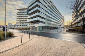 A modern multi-story building with a flat facade, large windows, and a pedestrian walkway. - Modern Apartment | Air Conditioning | Spa and Gym | Parking. (Wrocław)