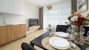 A modern living room with a dining area, a TV, and a kitchen. - Modern Apartment | Air Conditioning | Spa and Gym | Parking. (Wrocław)